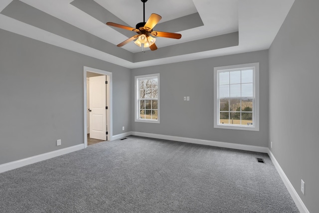 carpeted empty room featuring a tray ceiling and ceiling fan