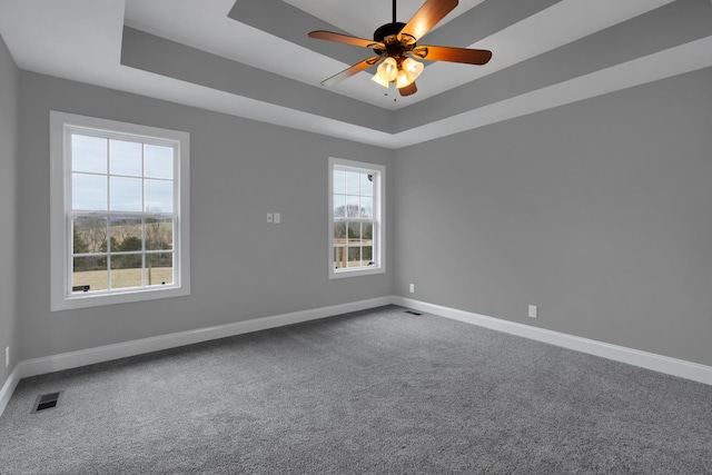 unfurnished room featuring carpet flooring, ceiling fan, and a raised ceiling