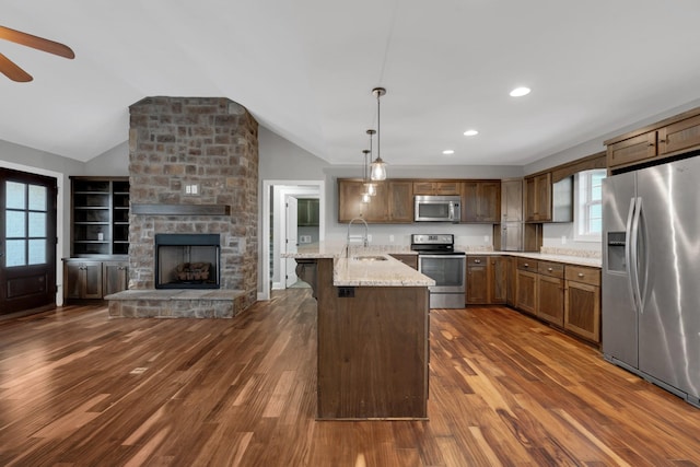 kitchen with light stone countertops, appliances with stainless steel finishes, dark hardwood / wood-style flooring, a center island, and hanging light fixtures