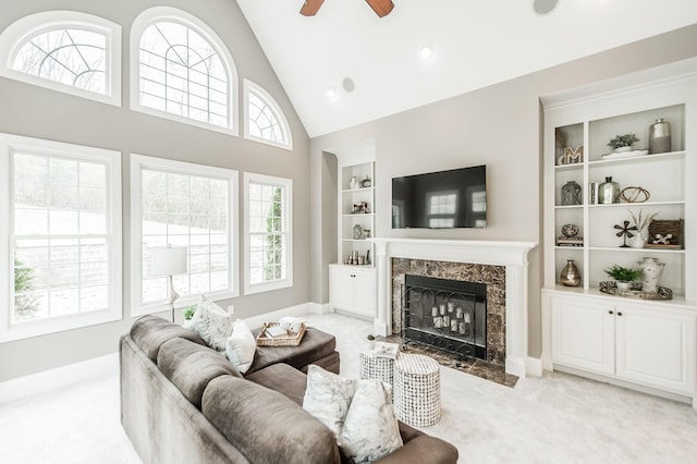 carpeted living room with built in shelves, ceiling fan, a fireplace, and high vaulted ceiling