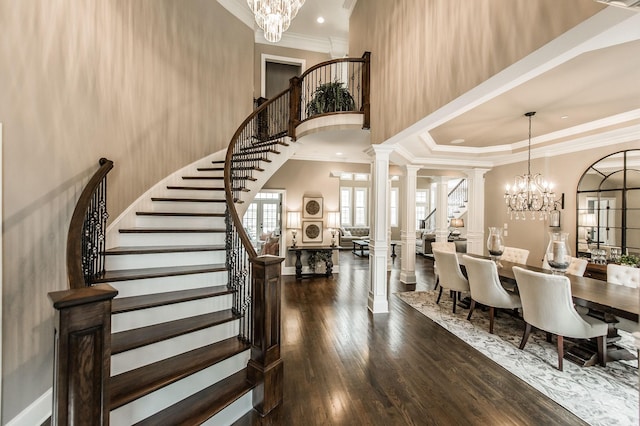 foyer with ornate columns, dark hardwood / wood-style flooring, crown molding, a chandelier, and a tray ceiling