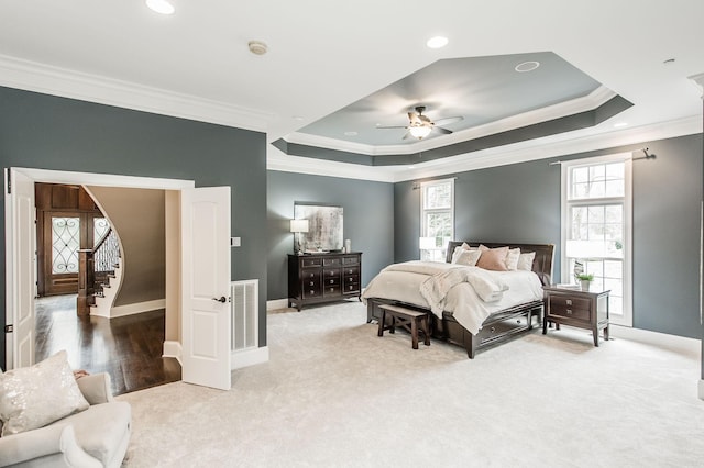 carpeted bedroom featuring a tray ceiling, ceiling fan, and crown molding