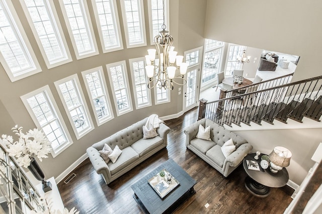 living room with dark hardwood / wood-style flooring, a towering ceiling, and a chandelier