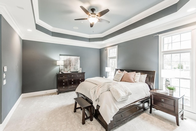 bedroom featuring ceiling fan, a raised ceiling, light colored carpet, and crown molding