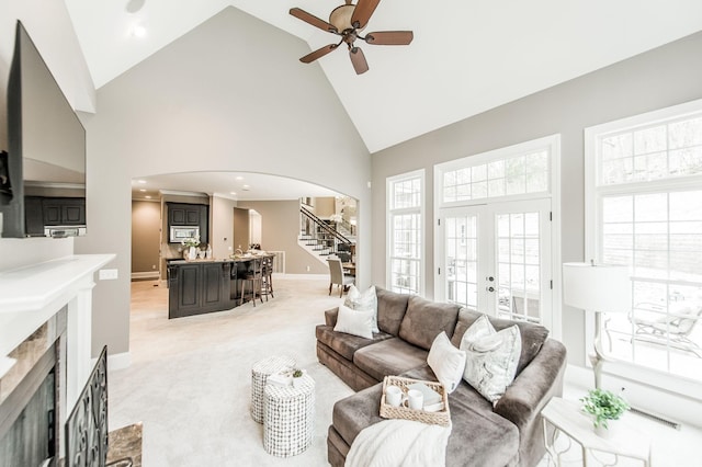 carpeted living room featuring a fireplace, french doors, high vaulted ceiling, and ceiling fan