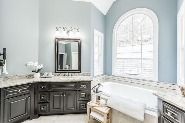 bathroom with a bath, vanity, and lofted ceiling