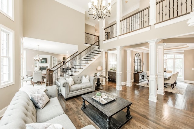 living room featuring a chandelier, a towering ceiling, dark hardwood / wood-style flooring, and crown molding