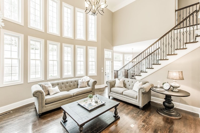 living room with dark hardwood / wood-style flooring, crown molding, a high ceiling, and an inviting chandelier