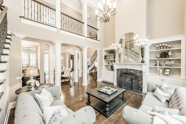 living room with a high end fireplace, dark wood-type flooring, a high ceiling, and an inviting chandelier