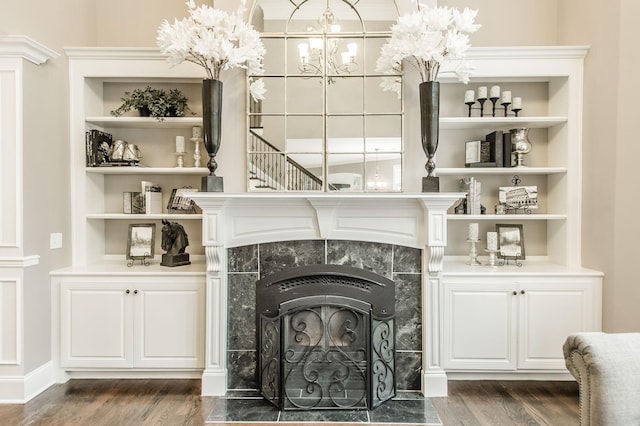 details with built in shelves, hardwood / wood-style flooring, and a tiled fireplace