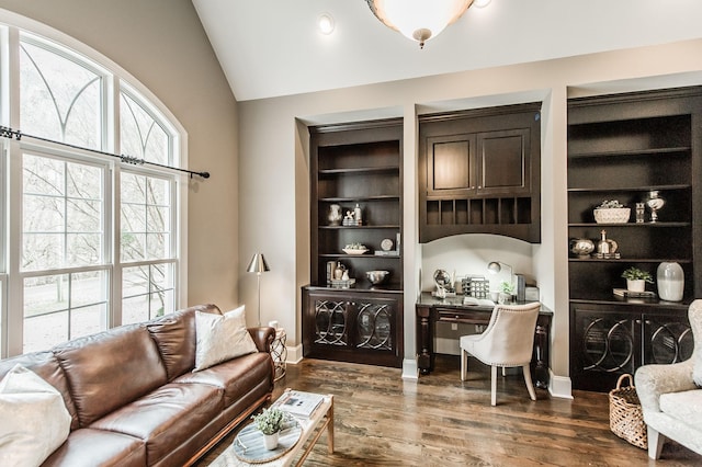 interior space featuring built in shelves, vaulted ceiling, and dark wood-type flooring