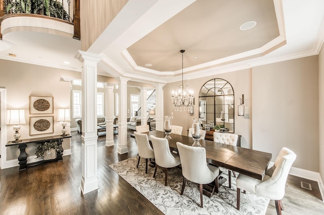 dining room featuring ornate columns, ornamental molding, a raised ceiling, an inviting chandelier, and dark hardwood / wood-style floors