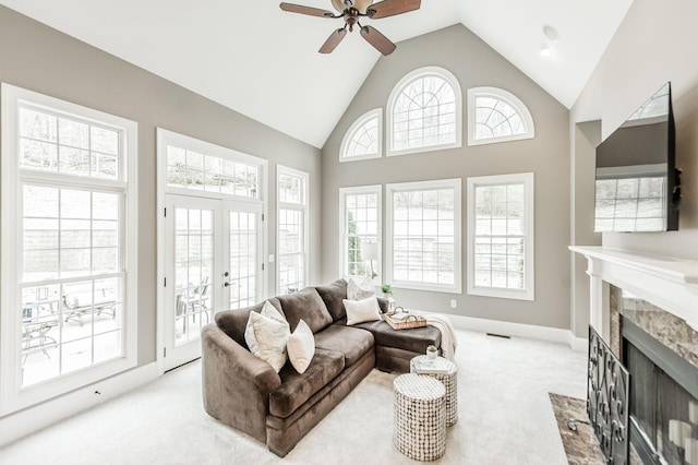 living room featuring a high end fireplace, french doors, ceiling fan, plenty of natural light, and light colored carpet