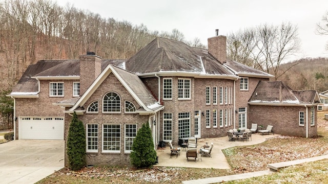 back of property with a patio area, a garage, and an outdoor hangout area