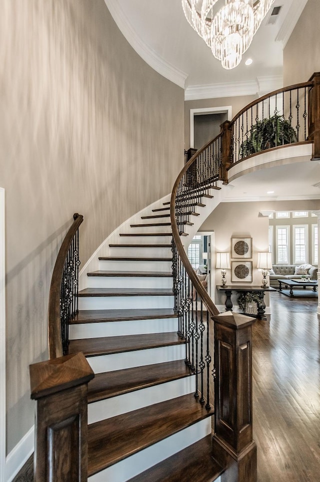 stairs with hardwood / wood-style flooring, ornamental molding, and a chandelier