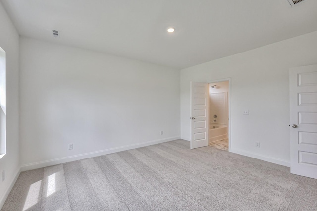 unfurnished bedroom featuring ensuite bath and light colored carpet