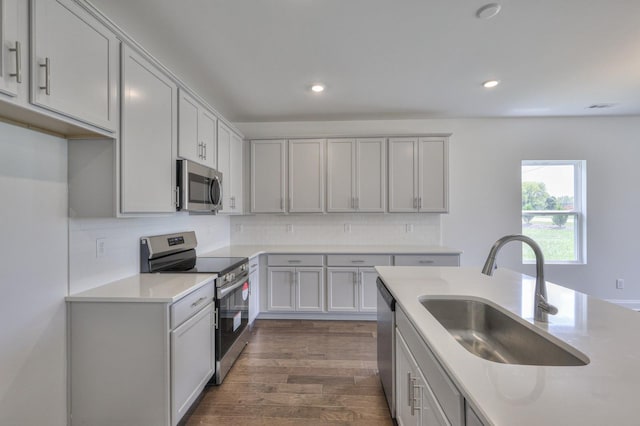 kitchen with decorative backsplash, stainless steel appliances, dark wood-type flooring, sink, and gray cabinets