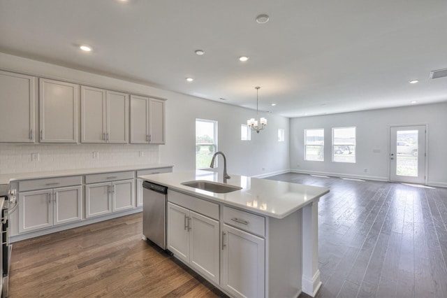 kitchen with a kitchen island with sink, sink, stainless steel dishwasher, tasteful backsplash, and dark hardwood / wood-style flooring