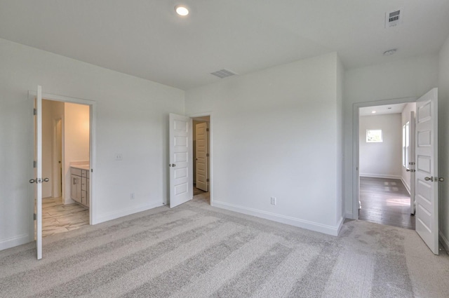 unfurnished bedroom featuring connected bathroom and light colored carpet