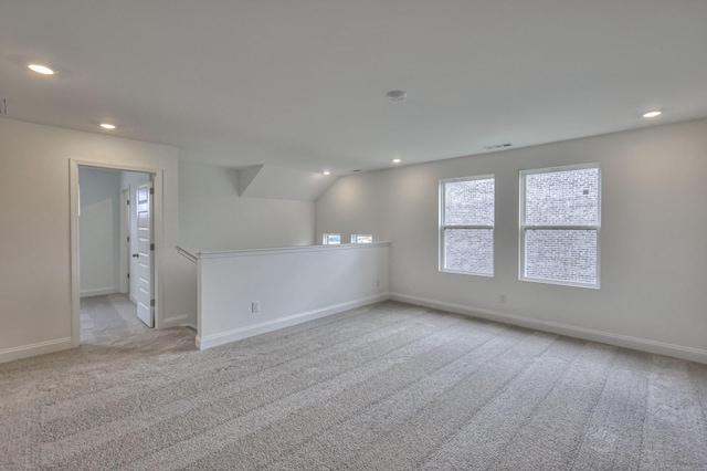 unfurnished room featuring light colored carpet and vaulted ceiling