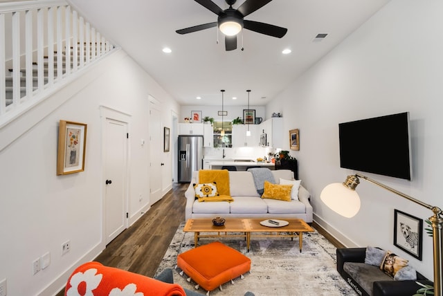 living room with ceiling fan and dark wood-type flooring