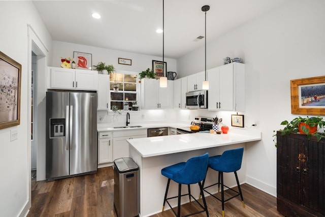 kitchen featuring kitchen peninsula, appliances with stainless steel finishes, white cabinetry, and pendant lighting