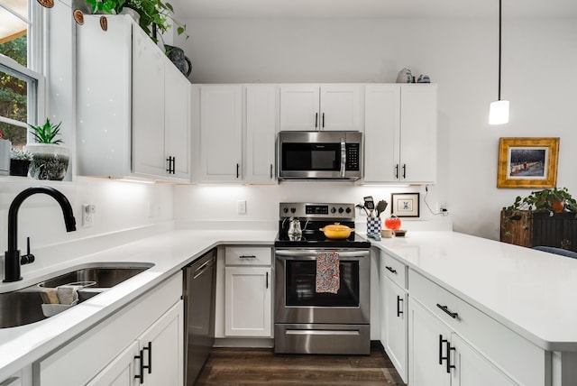 kitchen with white cabinetry, sink, dark hardwood / wood-style floors, pendant lighting, and appliances with stainless steel finishes