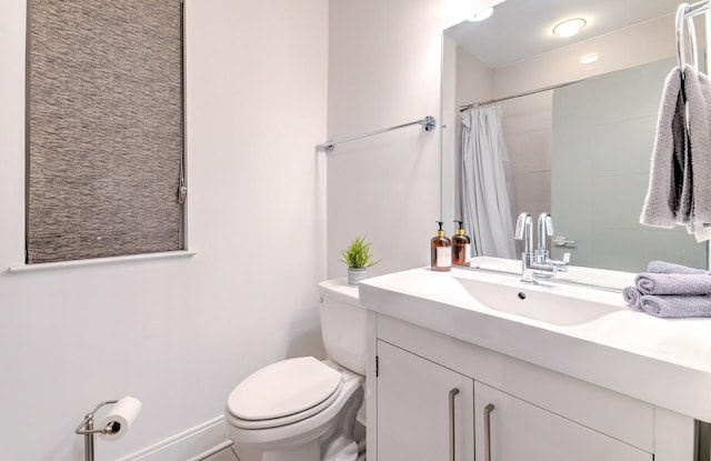 bathroom featuring toilet, vanity, and curtained shower