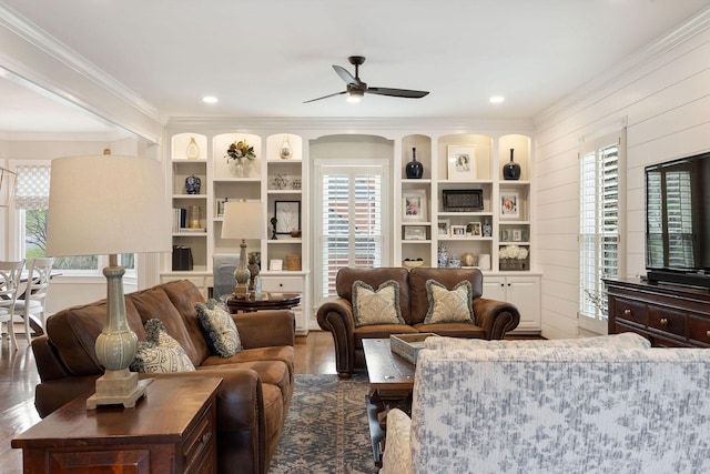 living room with wooden walls, ceiling fan, and ornamental molding