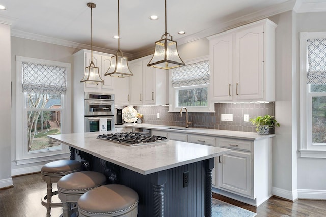 kitchen with appliances with stainless steel finishes, sink, decorative light fixtures, a center island, and white cabinetry