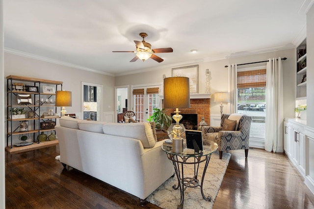 living room with dark hardwood / wood-style floors, ceiling fan, ornamental molding, and a fireplace