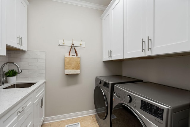 laundry area with sink, cabinets, crown molding, light tile patterned floors, and washer and dryer