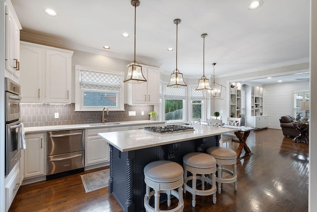 kitchen featuring a center island, sink, white cabinets, and hanging light fixtures