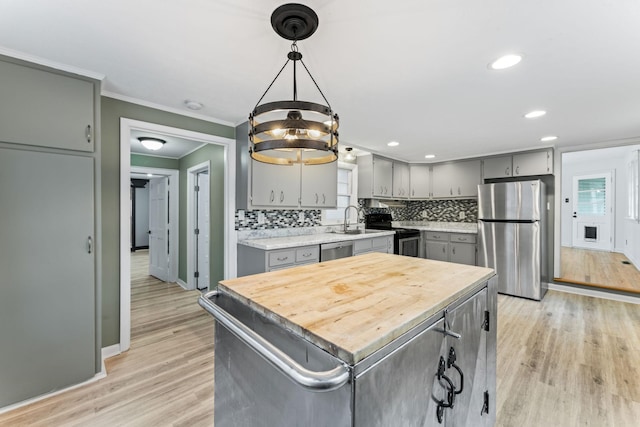 kitchen with light wood-type flooring, stainless steel appliances, a center island, gray cabinets, and hanging light fixtures