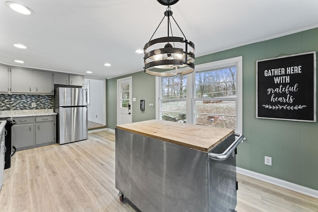 kitchen featuring gray cabinetry, pendant lighting, backsplash, stainless steel fridge, and light wood-type flooring