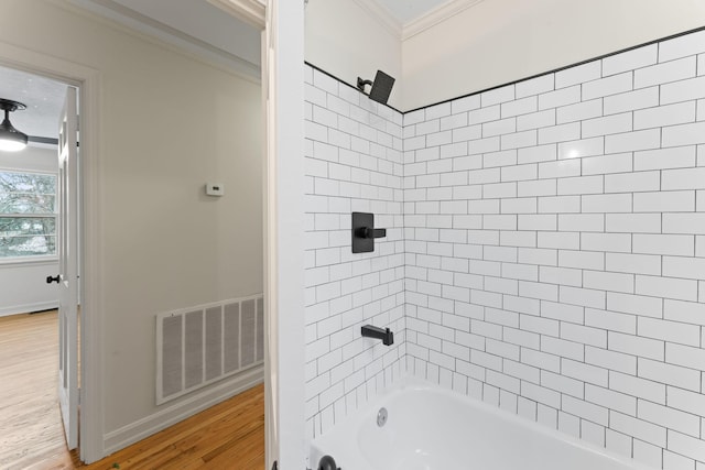 bathroom featuring hardwood / wood-style floors, tiled shower / bath combo, and ornamental molding