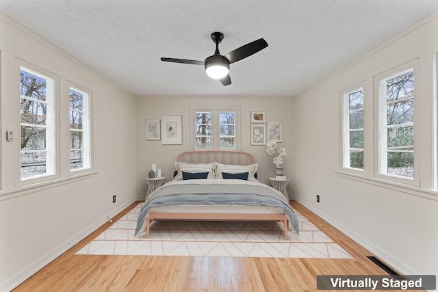 bedroom with a textured ceiling, light hardwood / wood-style floors, and ceiling fan