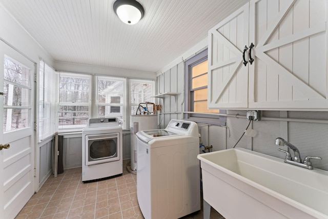 laundry area featuring washing machine and dryer, light tile patterned floors, sink, and water heater