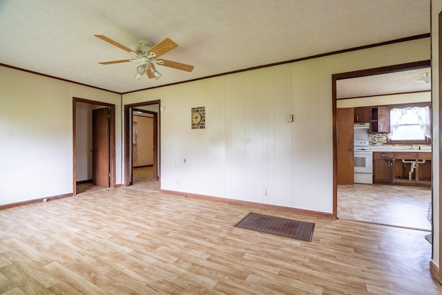 spare room with ceiling fan, light hardwood / wood-style flooring, crown molding, and a textured ceiling