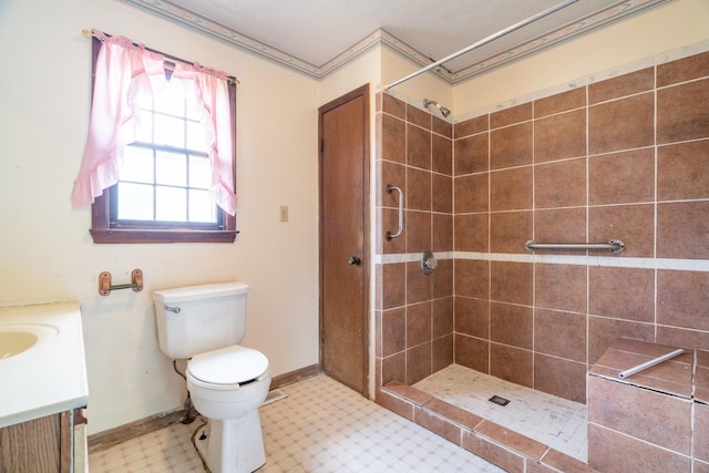 bathroom featuring a tile shower, vanity, and toilet