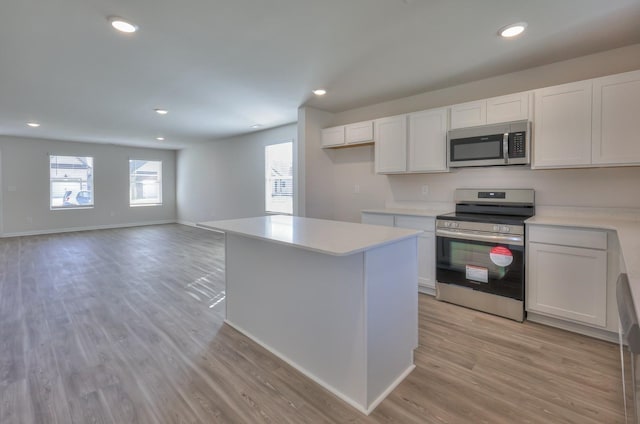 kitchen with white cabinetry, a center island, light wood-type flooring, appliances with stainless steel finishes, and a healthy amount of sunlight