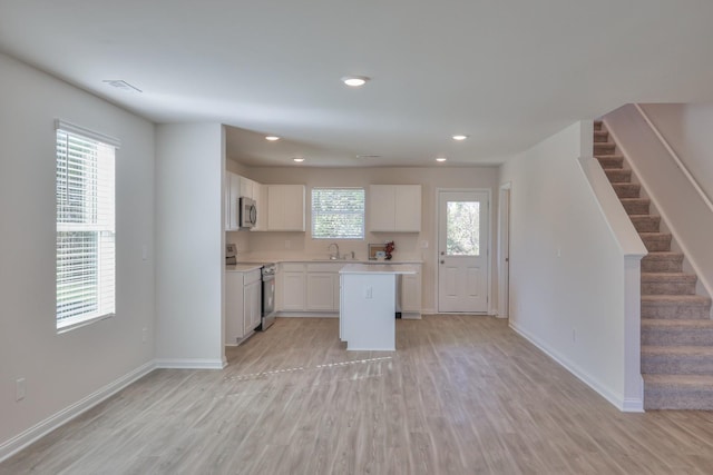 kitchen featuring a kitchen island, white cabinetry, appliances with stainless steel finishes, and light wood-type flooring