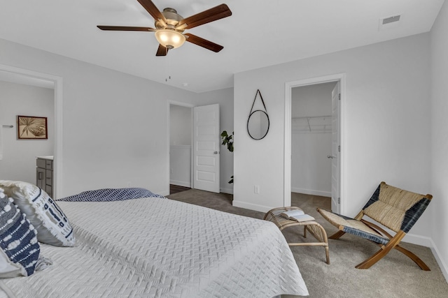 carpeted bedroom featuring a spacious closet, ceiling fan, ensuite bathroom, and a closet