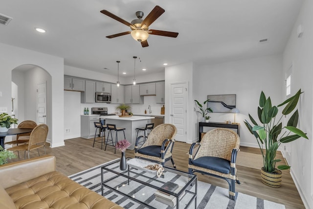 living room with ceiling fan, sink, and light hardwood / wood-style flooring