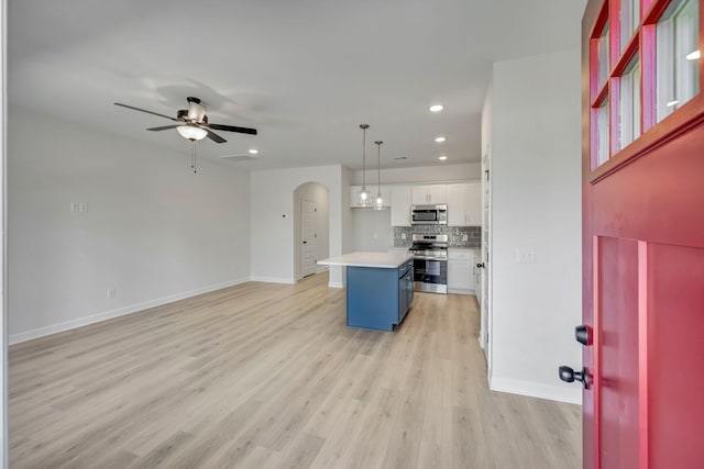 kitchen with white cabinetry, ceiling fan, stainless steel appliances, pendant lighting, and a center island