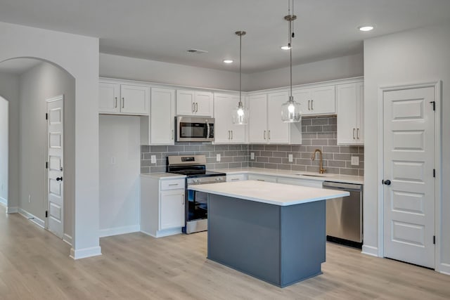 kitchen featuring a center island, white cabinetry, stainless steel appliances, sink, and hanging light fixtures