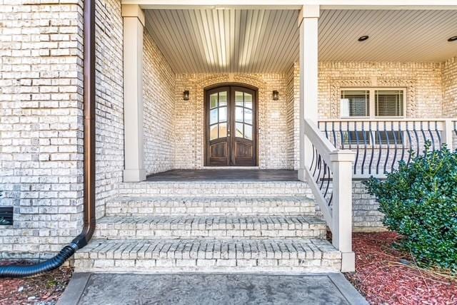 entrance to property with brick siding and covered porch