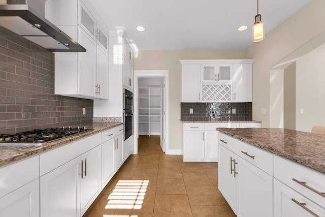 kitchen featuring decorative light fixtures, light tile patterned floors, stainless steel gas stovetop, white cabinets, and wall chimney exhaust hood