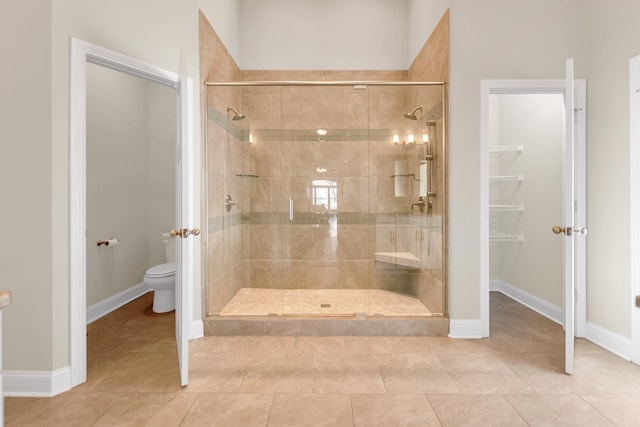 full bath with tile patterned flooring, toilet, baseboards, and a stall shower