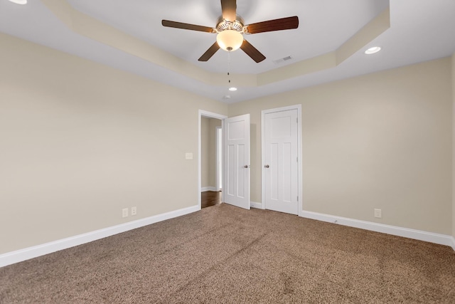 unfurnished bedroom with visible vents, a raised ceiling, baseboards, and carpet floors